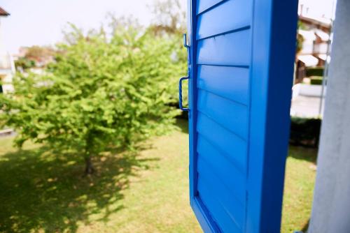 a blue door of a house with a tree at Cà del Mar rustico a Jesolo con giardino e piscina privati ad uso esclusivo # in Jesolo