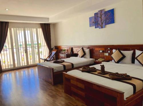 a hotel room with two beds and a large window at Thmor Da Guest House in Kampong Cham
