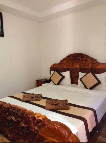 a bedroom with a large bed with a wooden headboard at Thmor Da Guest House in Kampong Cham