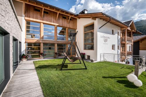 a house with a lawn with a chair in the yard at Hotel La Fradora - Dolomites Hotel in San Cassiano