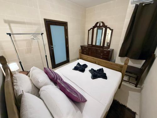 a bedroom with a white bed with purple pillows and a couch at Traditional Maltese 3BD Apartment with Front & Back Balconies - Close to Gozo Ferry in Nadur
