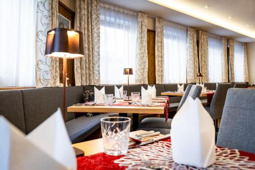 a dining room with tables and chairs and curtains at Hotel Alpenrose in Zauchensee