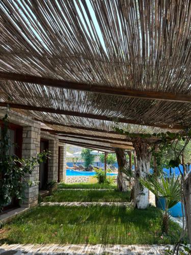 a wooden pergola in a yard with a green lawn at Palermiti Luxury Rooms in Himare