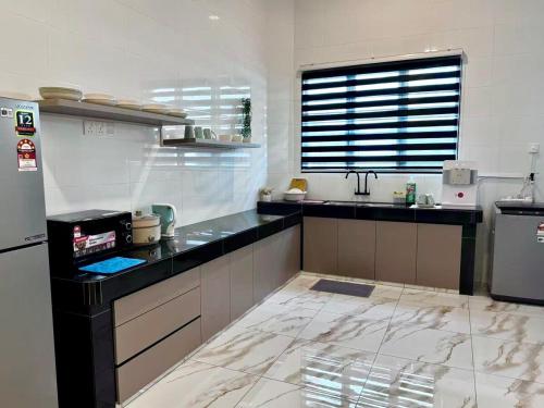 a kitchen with black counter tops and a refrigerator at Warm & Cozy Home in Kampong Duson Gilap