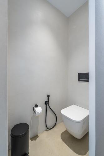 a white bathroom with a toilet and a hose at Petradi Studios & Villa in Aegiali