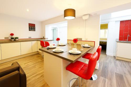 a kitchen and living room with a table and red chairs at Maidstone House Kent By Smart Corporate Stays in Maidstone