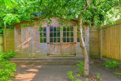 a wooden cabin with a door and a tree at Maidstone House Kent By Smart Corporate Stays in Maidstone