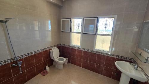 a bathroom with a toilet and a sink and windows at Nekor Bay Villa in Al Hoceïma