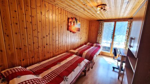 three beds in a room with wooden walls and a window at Beau Sejour 2 - Appartement 6 personnes - Evolene in Evolène
