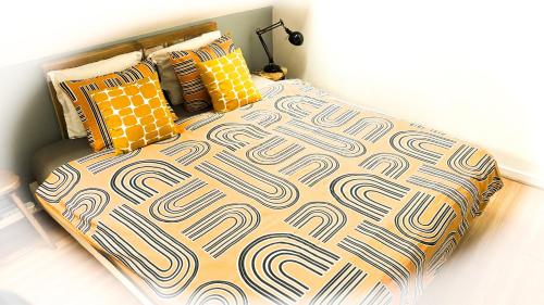 a bed with a comforter and pillows on it at Appartement agreable et zen in Boulogne-sur-Mer