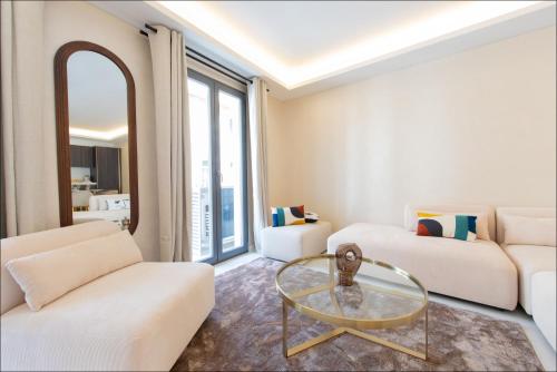 ein Wohnzimmer mit weißen Möbeln und einem Glastisch in der Unterkunft Hôtel particulier Marceau - Centre - Neuf - Suites de 3 à 28 chambres in Cannes