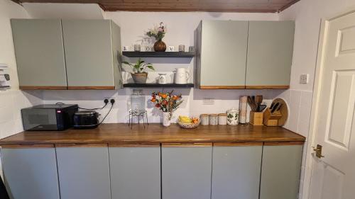 a kitchen with white cabinets and a wooden counter top at Stay your way in Huyton with Roby