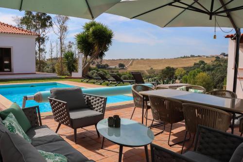a patio with a table and chairs and a pool at Herdade Paraíso da Moçarria in Santarém
