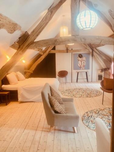 - un salon avec un lit et une chaise dans l'établissement Le domaine aux herbes folles, à Stigny