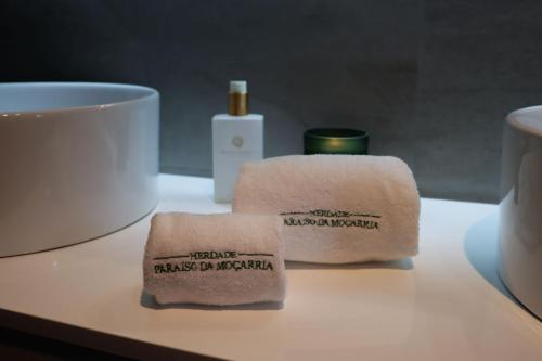 a pair of towels sitting on a table next to a cup at Herdade Paraíso da Moçarria in Santarém