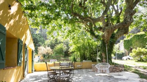 un patio avec des tables et des chaises sous un arbre dans l'établissement Maison sur terrain nature 2200m2, à Cuers