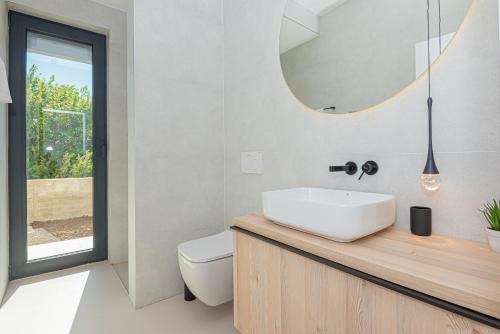 a bathroom with a white sink and a mirror at Seafront Villa Serena with pool and seaview in Privlaka