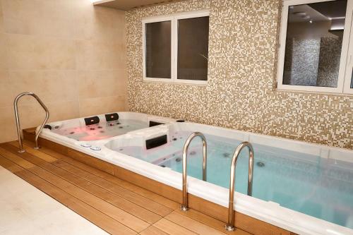a jacuzzi tub in a bathroom with two windows at LAGUNA Apartament Polanica Residence 14 SPA z tarasem in Polanica-Zdrój