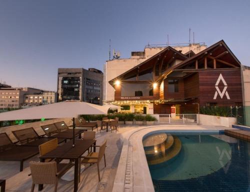 a hotel with a pool and tables and chairs at Studio ao lado do Museu do Amanhã in Rio de Janeiro