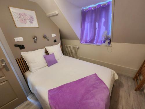 a bedroom with a large white bed with purple pillows at chambre mauve in Saint-Nicolas-dʼAliermont
