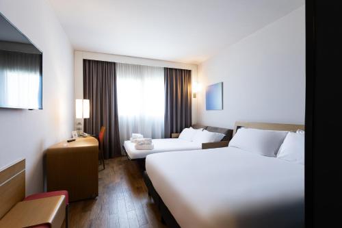 a hotel room with two beds and a couch at Novotel Caserta Sud in Caserta
