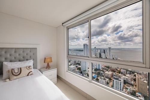een slaapkamer met een groot raam met uitzicht op de stad bij Palmetto Beach by MOME in Cartagena