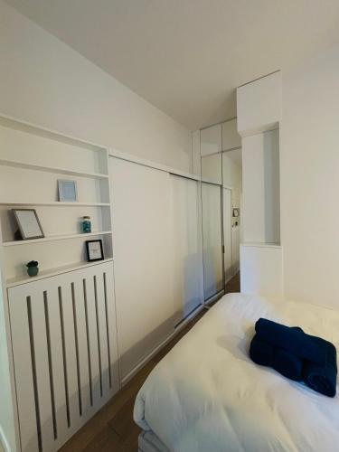 - une chambre dotée d'un lit blanc avec un oreiller bleu dans l'établissement Appartement Malesherbes Wagram, à Paris
