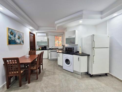 a kitchen with white appliances and a table and chairs at L'Orchidée - Suites de Luxe avec Piscine Chauffée et Vue sur le Lac de Tunis in Tunis