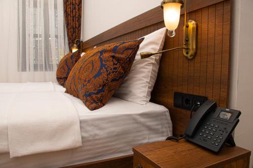 a hotel room with a phone next to a bed at TASHAN1699 Otel ve Restoran in Amasya