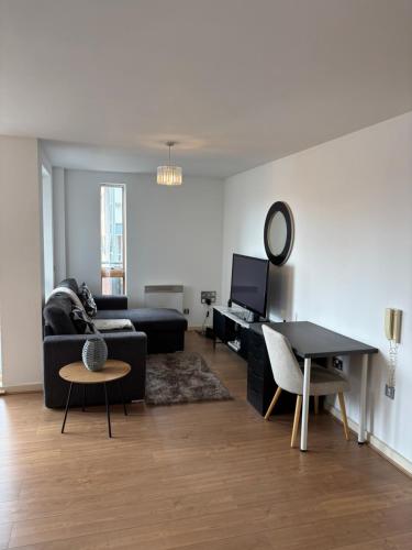 a living room with a black couch and a table at LUX 2bed City Centre and AO Arena Free Parking Modern Apt in Manchester