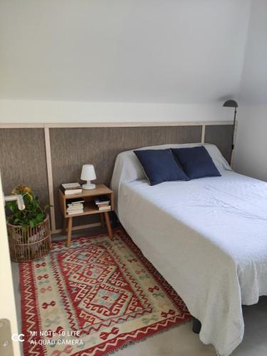 a bedroom with a bed and a table with a blue pillow at Cottage Playa Cabeiro in Porto do Son