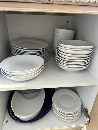 a group of white plates and bowls on a shelf at Beachfront Apt With Amazing View at Marbella Juan Dolio in Juan Pedro