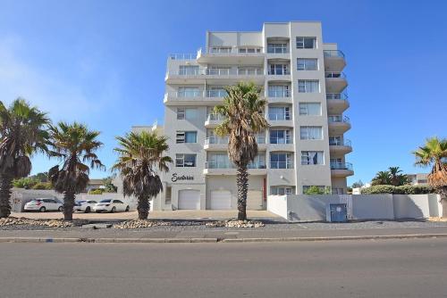 a tall white building with palm trees in front of it at Mountain and Oceanview at Blouberg in Cape Town