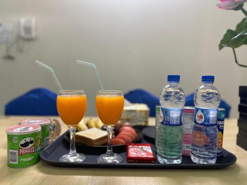 two glasses of orange juice and bottles of water on a tray at The Ambassador Hotel Dhanmondi in Dhaka