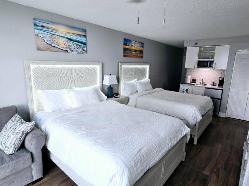 デイトナビーチにあるNew updated Daytona Oceanview w/kitchenette, poolのベッド2台とソファのある寝室