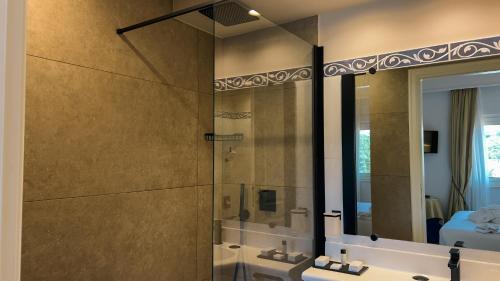 a bathroom with a shower and a sink and a mirror at Altafiumara Resort & Spa in Villa San Giovanni