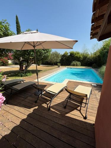 un patio avec deux chaises et un parasol à côté d'une piscine dans l'établissement Mas de charme provencal, à Cavaillon