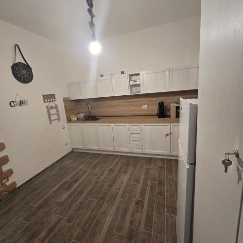 a kitchen with white cabinets and a wooden floor at Miluna Affittacamere in Siniscola