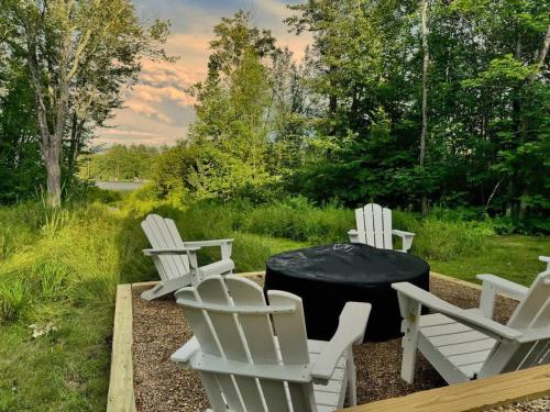 a group of white chairs and a table with a black table cloth at Winnisquam Landing Lakefront Firepit Deck in Tilton