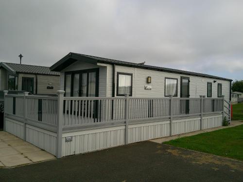 a house with a fence in front of it at Kings Ashington 6 Berth Central Heated Enclosed Veranda in Chapel Saint Leonards
