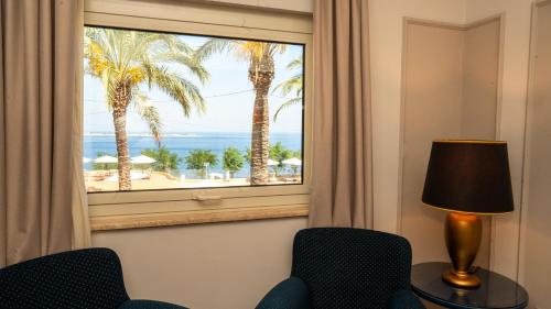 a room with a window with palm trees and the ocean at Altafiumara Resort & Spa in Villa San Giovanni