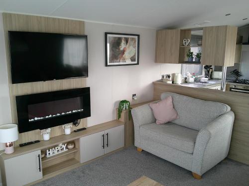 a living room with a chair and a flat screen tv at Kings Ashington 6 Berth Central Heated Enclosed Veranda in Chapel Saint Leonards