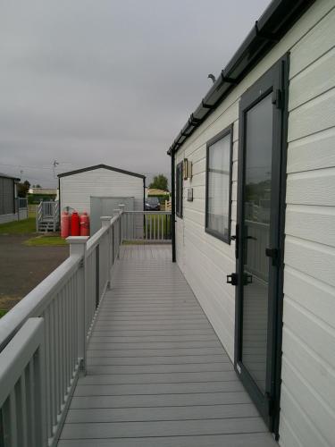 a boardwalk leading to a covered porch on a house at Kings Ashington 6 Berth Central Heated Enclosed Veranda in Chapel Saint Leonards