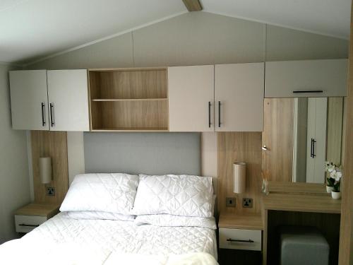 a bedroom with white cabinets and a bed at Kings Ashington 6 Berth Central Heated Enclosed Veranda in Chapel Saint Leonards