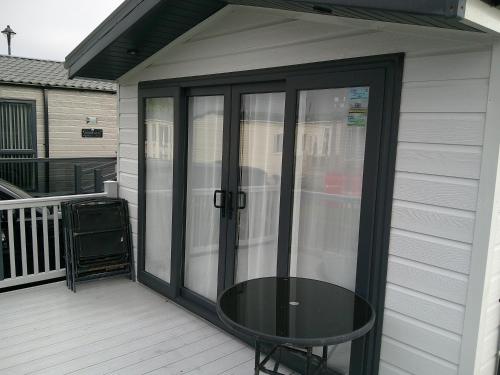 a glass door with a table on a porch at Kings Ashington 6 Berth Central Heated Enclosed Veranda in Chapel Saint Leonards