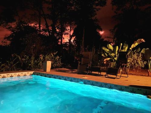 a swimming pool at night with two chairs and a table at Private Cabina at Yoga Center in Ojochal