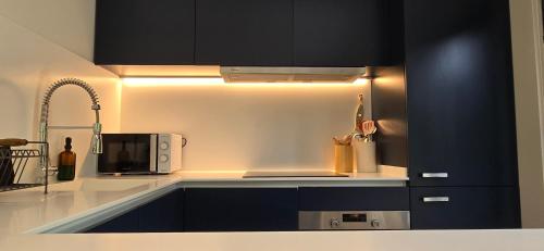 a kitchen with dark blue cabinets and a microwave at Cottage Playa Cabeiro in Porto do Son