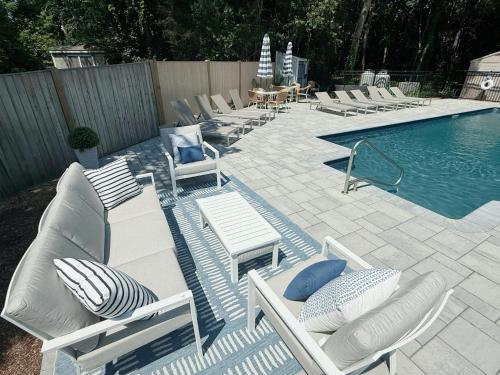 a row of lounge chairs next to a swimming pool at The Seagrove Suites & Guest Rooms in Eastham