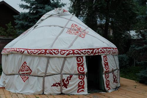 una tenda a cupola rossa e bianca su un ponte di legno di 70 Years Old Yurt Experience Almaty a Almaty