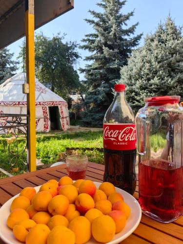 un piatto di arance su un tavolo accanto a una bottiglia di Coca-Cola di 70 Years Old Yurt Experience Almaty a Almaty